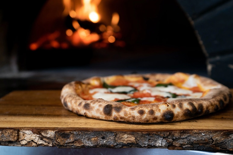 A finished pizza in a wood fired oven.