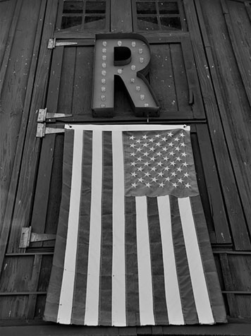 Black and white of a US flag hanging from the Rebel Ranch barn.